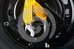 On the black background of the wheel of the car, yellow tow rope and a Jack for mounting