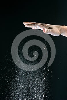 On a black background, a woman`s hand pours white flour like snow for baking
