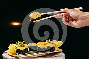 Black Baked roll in the Chinese chopsticks in hand over the dish