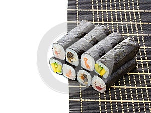 Black bamboo mat with sushi isolated on white background