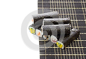 Black bamboo mat with sushi isolated on white background