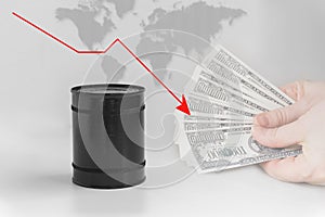 Black barrel with oil on the background of the world map, red graph down and hands that hold money.Grey simple background.The