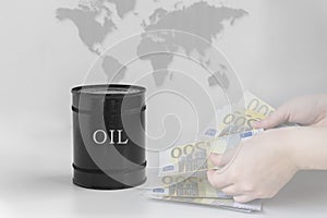 Black barrel with oil on the background of the world map, red graph down and hands that hold money.Grey simple background.The