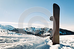 Black base snowboard in a snow with white mountains in the background. Concept of end beginning of ski season.Goderdzi ski resort