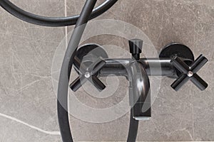 Black bathroom faucet in gray bathroom interior.