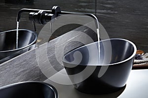 black Bathroom water mixer in modern bathroom. Water tap made of dark material, Black sink