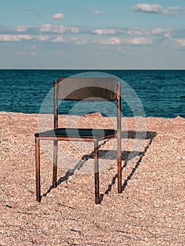 Black beach chair on empty sand beach with blue sea water background Minimalism style autumn travel relaxation No people