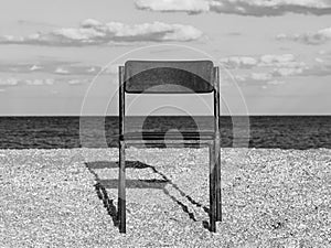 Black beach chair on empty sand beach with blue sea water background Minimalism style autumn travel relaxation No people