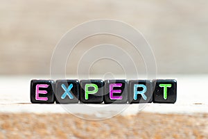 Black bead with letter in word expert on wood background