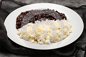 Black beans and boiled rice on white dish.