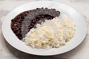 Black beans and boiled rice on white dish.