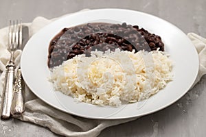 Black beans and boiled rice on white dish.