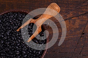 Black beans in scoop on wooden background