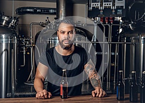 Black man manufacturer presenting craft beer in the microbrewery.