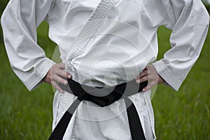 Black belt in karate. Hands on the belt. White kimono. Place for text.