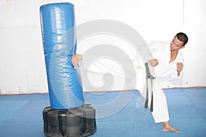 Black belt Karate man practicing in a sandbag photo