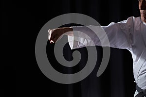 With a black belt, an old athlete beats a punch on a black background