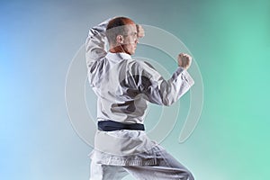 A black belt trainer performs formal exercises against a colored background with blue and green tints