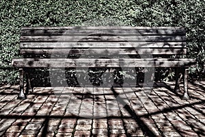 Black bench on a bright sunny day on a background of foliage with wrought iron legs in grunge style