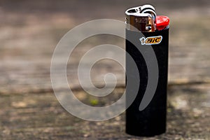Black Bic cigarette lighter on aged pine wood boards, space for text.