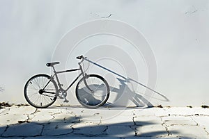 Black Bicycle Leaning Against a White Wall in Bright Sunlight