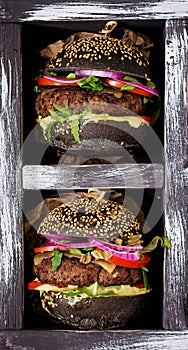 Black big sandwich - black hamburger with juicy beef burger, cheese, tomato, and red onion in box