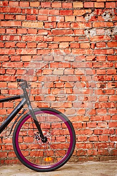 Black bike against red brick wall.