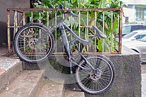 Black bike leaning against metal fence