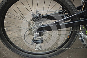 Black bike wheel. Bike details on street. Spokes and tire