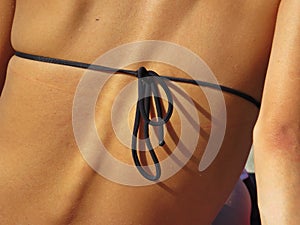 Black Bikini String Knot Closeup on Back of Attractive Beautiful Woman with Visible Spine Backbone