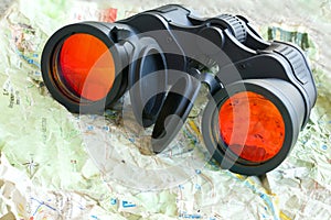 Black binoculars on a shrivelled map. Closeup