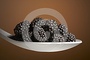 Black blackberries on spoon