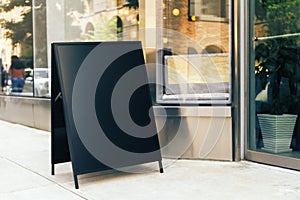 Black blank signboard stand near the entrance to the coffee shop, mock up