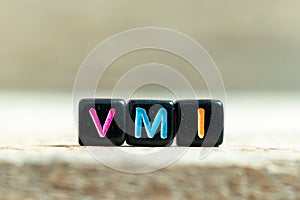 Black block with word VMI abbreviation of vendor managed inventory on wood background