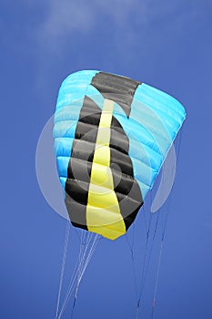 Black, blue and yellow kite in the blue sky