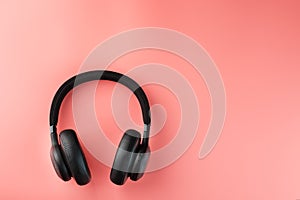 Black bluetooth headphones on a pink background top view. In-Ear Headphones for DJs