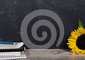 Black board background with stack of colourful notebooks