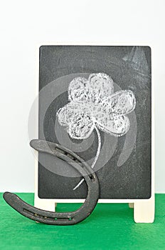 A black board with a four leaf clover and a horseshoe