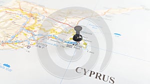 A black board pin stuck in Ayia Napa on a map of Cyprus