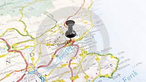 A black board pin stuck in Dundee on a map of Scotland photo