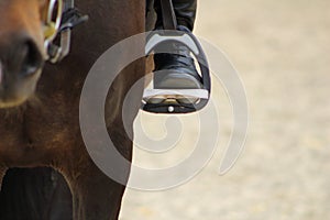 black boot of rider in the stirrup tighten on the horse, the foot in the stirru