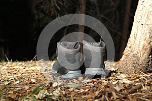 Black boots in the dark forest between trees ready for hiking in the mountains to explore at night