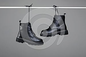 Black boots are hung by laces. fashion shoes still life