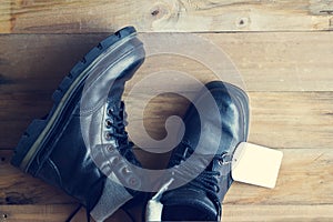 Black boots with label tag on wooden background