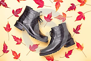 Black boots and red leaves on a yellow background. Autumn sale concept