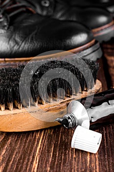 Black boots on wooden background with polishing equipment, brush and polish cream. Macro. Closeup.