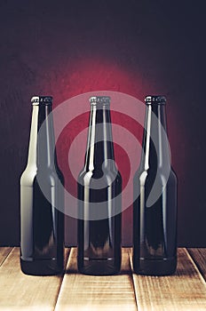 black bottle of beer on a red background of a wooden shelf/black bottle of beer on a red background of a wooden shelf. Toned and