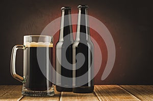 black bottle and glass beer on a dark background with red light/black bottle and glass beer on a dark background with red light.