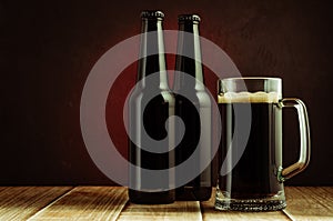 black bottle and glass beer on a red background/black bottle and glass beer on a red background of a wooden shelf. Copyspace and