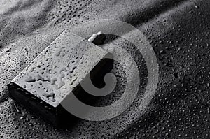 Black bottle of parfume with open cap on black water drops background.Closeu shot